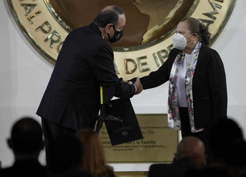 Guatemalan Attorney General Consuelo Porras is congratulated by President Alejandro Giammattei, left, after she was sworn in for another four-year term, at the National Palace in Guatemala City, Monday, May 16, 2022. (AP Photo/Moises Castillo)