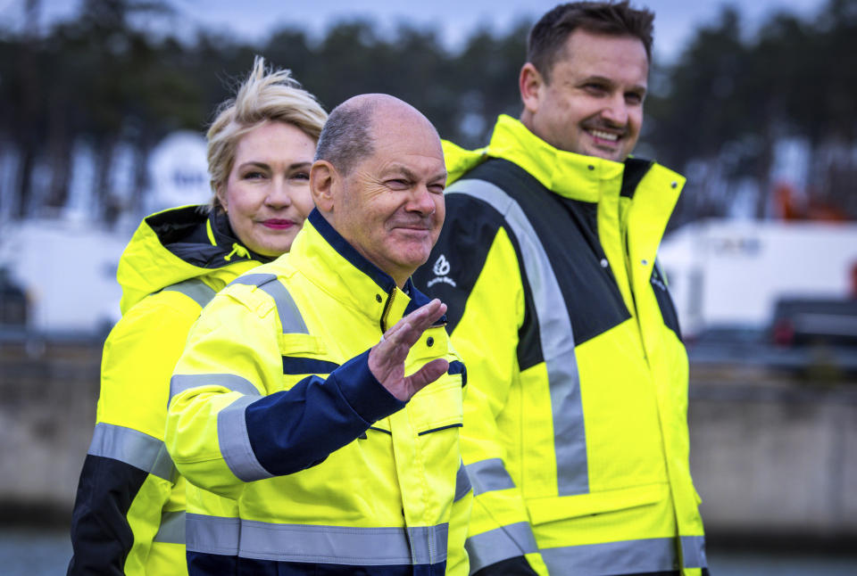 German Chancellor Olaf Scholz, front, Manuela Schwesig, Minister President of Mecklenburg-Western Pomerania, left, and Stephan Knabe, Chairman of the Supervisory Board of operator Deutsche Regas walk through the industrial port to the LNG terminal with processing vessel "Neptune" in Lubmin, Germany, Saturday Jan. 14, 2023. (Jens Buttner/dpa via AP)