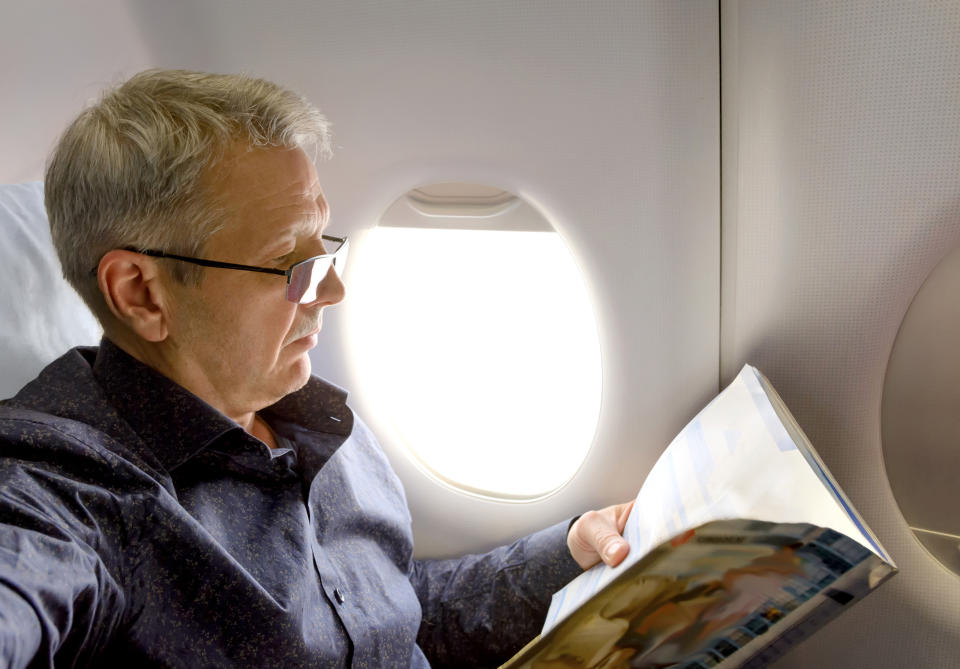 Older man reading a magazine on an airplane