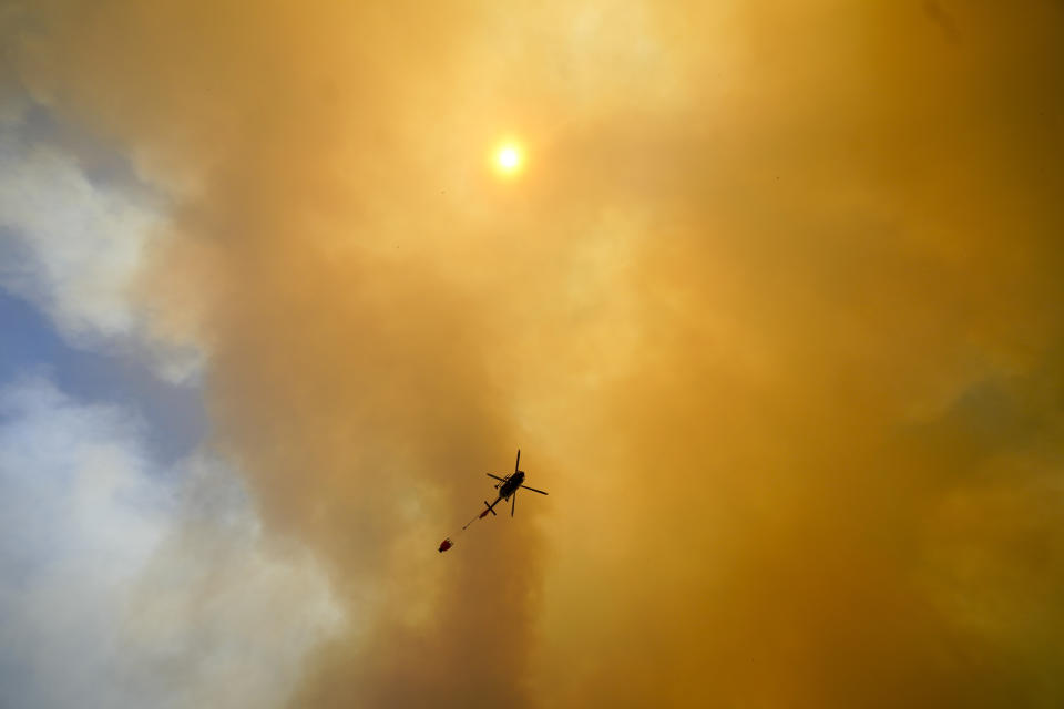 Plumes of smoke rise into the sky as a helicopter flies over a forest fire that has spread to Vina del Mar, Chile, Saturday, Feb. 3, 2024. Officials say intense forest fires burning around a densely populated area of central Chile have left several people dead and destroyed hundreds of homes. (AP Photo/ Esteban Felix)