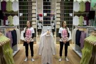 A shop assistant (L) is reflected in the mirror as she stands in the Uniqlo Global flagship store during a preopening in Berlin, April 10, 2014. REUTERS/Axel Schmidt