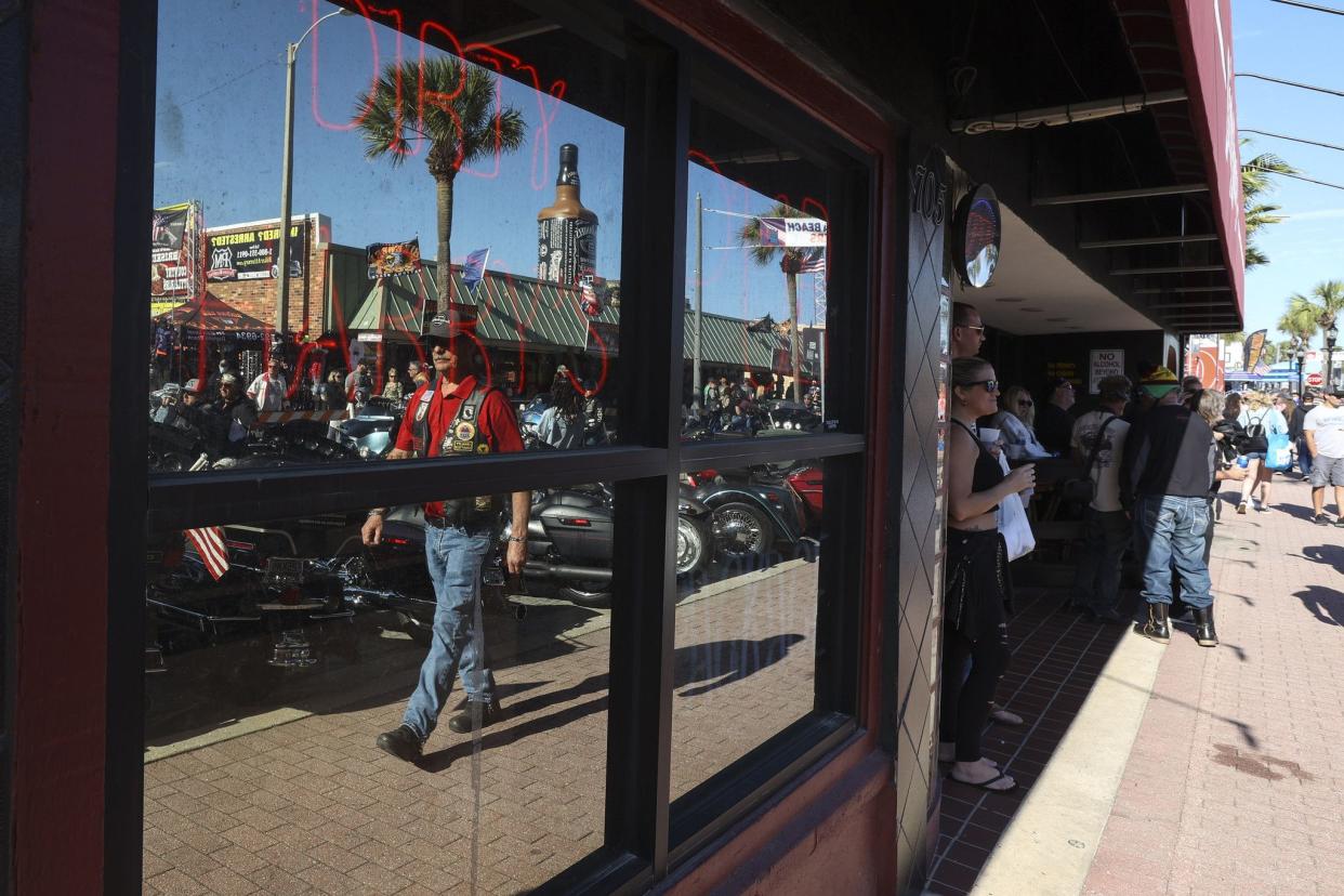 A man is reflected in the window outside of Dirty Harry’s Pub on Main Street in Daytona, FL during Bike Week on March 5, 2021. (Sam Thomas/Orlando Sentinel)