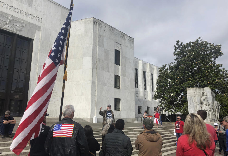 In this photo taken Sunday, June 23, 2019, a small crowd of local Republicans show their support of a Republican walkout outside the Oregon State Capitol in Salem, Ore. The gathering took place only a day after the Senate President ordered the statehouse to close over a "possible militia threat," the latest escalation in a Republican walkout over proposed climate policy that has put Democrats' top legislative priorities at risk. (AP Photo/Sarah Zimmerman)