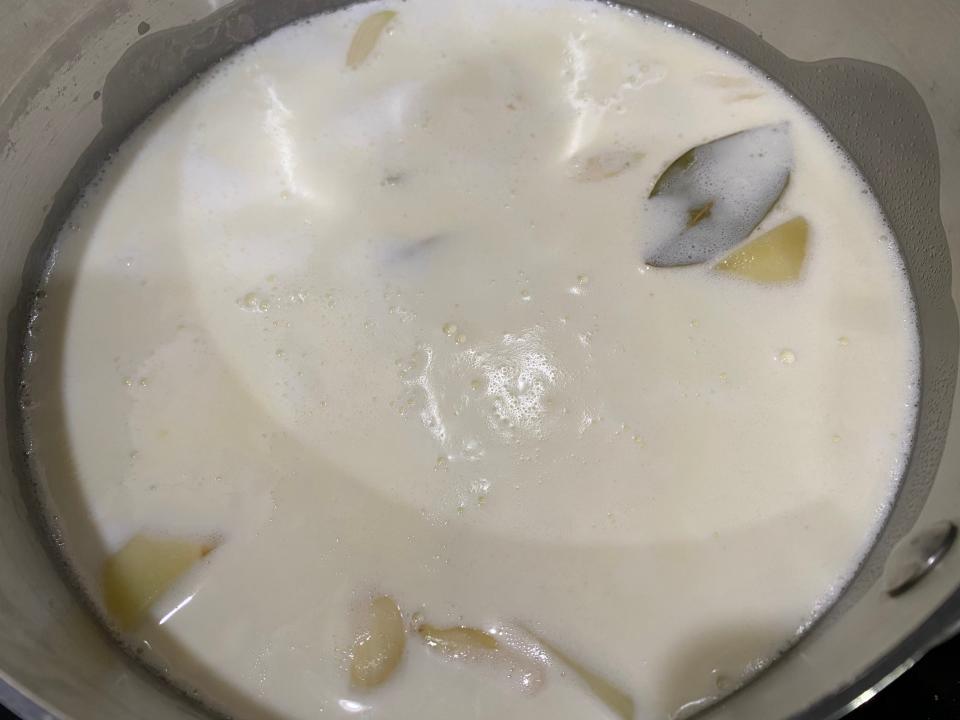 Yukon Gold potatoes, two smashed garlic cloves, and one bay leaf in the pot full of dairy