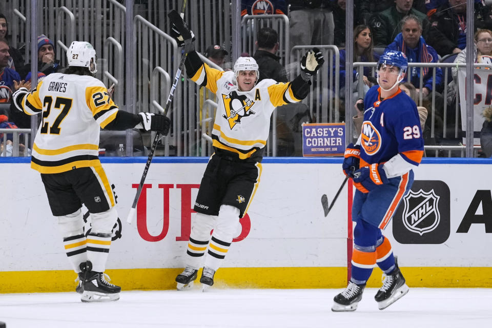 Pittsburgh Penguins' Evgeni Malkin, center, celebrates with Ryan Graves (27) as New York Islanders' Brock Nelson (29) looks away after Malkin scored a goal during the second period of an NHL hockey game Wednesday, Dec. 27, 2023, in Elmont, N.Y. (AP Photo/Frank Franklin II)