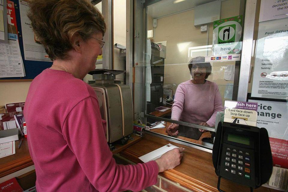 Mujer envía una carta en la oficina de correos