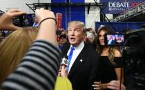 Republican nominee Donald Trump (C) speaks with reporters in the "Spin Room" as Melania Trump looks on