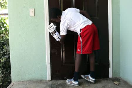 Handicapped Haitian boy Stevenson Joseph, learns to use a 3D-printed prosthetic hand to open a door at the orphanage where he lives in Santo, near Port-au-Prince, April 28, 2014. REUTERS/Marie Arago