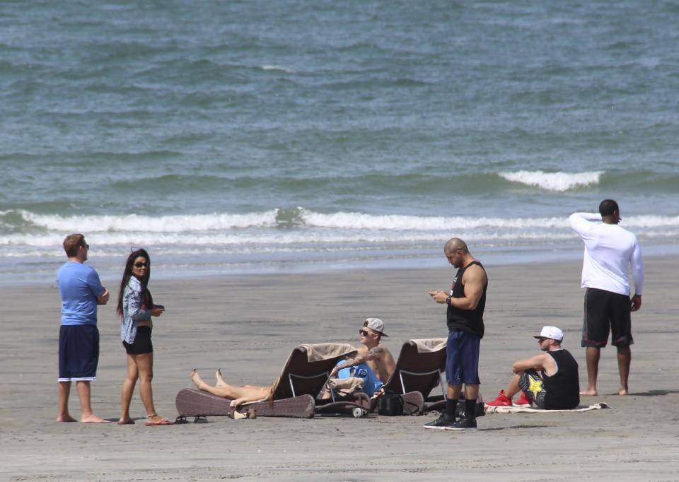 Justin Bieber, center, sits on the beach with a group of people in Punta Chame, Panama, Saturday, Jan. 25, 2014. A Panamanian radio and television host says trouble-plagued pop star Justin Bieber has been relaxing on a beach in Panama on a vacation from the United States. Eddy Vasquez was filming a show at the Pacific Coast resort in Punta Chame, about 90 miles west of Panama City, when he spotted Bieber and members of his entourage walking along the beach. (AP Photo/Eddy Vasquez)