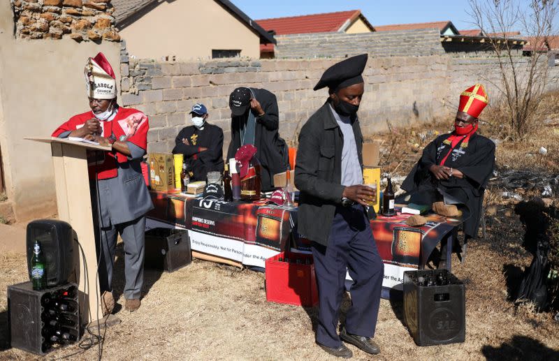 A congregant holds a glass of beer as "Pope" Tsietsi Makiti conducts a service at the Gabula church