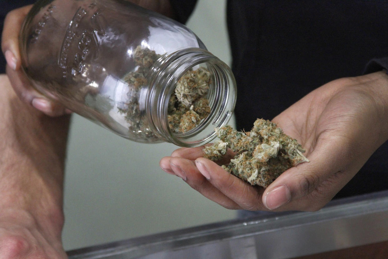 FILE - In this Feb. 20, 2015, file photo, Alaska Cannabis Club CEO Charlo Greene prepares to roll a joint at the medical marijuana dispensary in Anchorage, Alaska. A credit union is launching a pilot program to begin serving marijuana businesses in Alaska, giving the cash-only industry a financial option after banks shunned the industry. Credit Union 1 announced Thursday, Nov. 29, 2018, its move comes with no political or moral position. (AP Photo/Mark Thiessen, File)