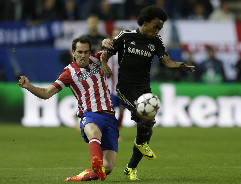 Atletico's Diego Godin, left, challenges Chelsea's Willian during the Champions League semifinal first leg soccer match between Atletico Madrid and Chelsea at the Vicente Calderon stadium in Madrid, Spain, Tuesday, April 22, 2014 .(AP Photo/Paul White)