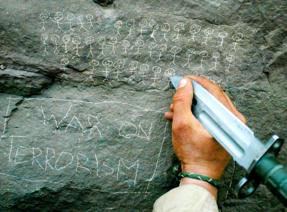 <p>United States Army 10th Mountain Division soldier Jorge Avino from Miami, Florida carves the body count that their mortar team has chalked up on a rock, March 9, 2002 near the villages of Sherkhankheyl, Marzak and Bobelkiel, in Afghanistan. (Photo: Joe Raedle/Reuters) </p>