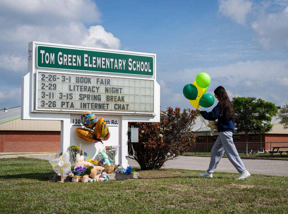 Anabell González coloca globos en un monumento que se forma en la Escuela Primaria Tom Green en Buda el 23 de marzo después de que una clase se viera involucrada en un accidente de autobús que dejó a un estudiante muerto el día anterior.