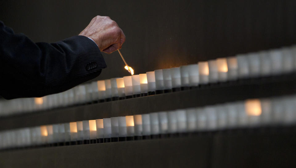 Nobel Peace Prize laureate and Holocaust survivor Elie Wiesel lights a candle as he toured the Hall of Remembrance at the Holocaust Memorial Museum, with President Barack Obama, Monday, April 23, 2012, in Washington. (AP Photo/Carolyn Kaster)