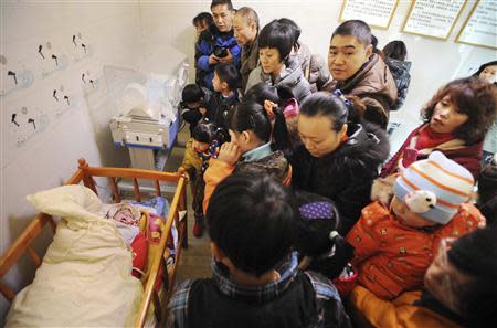 Residents visit an abandoned baby (L) lying in a crib at a baby hatch in Guiyang, Guizhou province January 12, 2014. REUTERS/Stringer