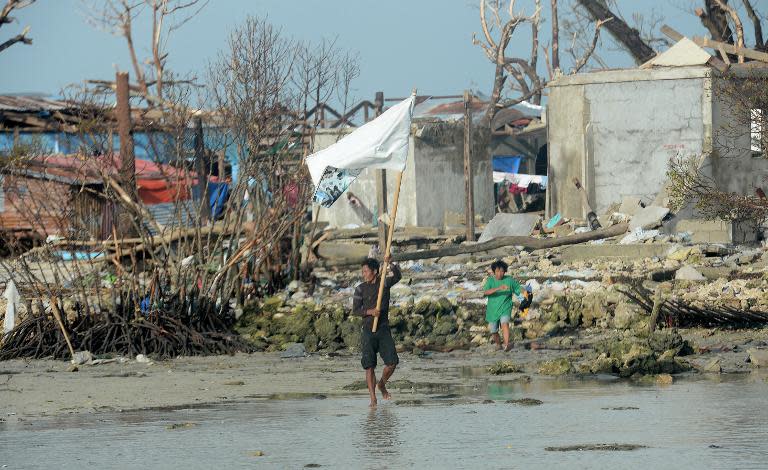A resident waves a white flag as a rescue helicopter lands to deliver food on Victory Island off of the town of Guiuan in Eastern Samar province, central Philippines on November 11, 2013