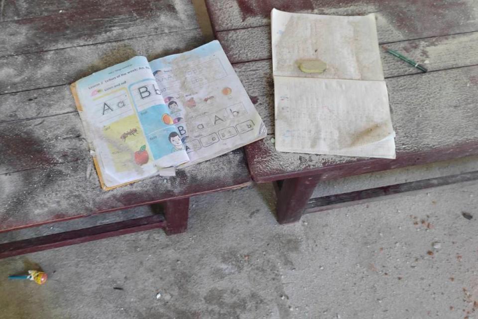 An alphabet book and a notebook lie on top of an elevated wooden floorboard of a middle school in Let Yet Kone village (AP)