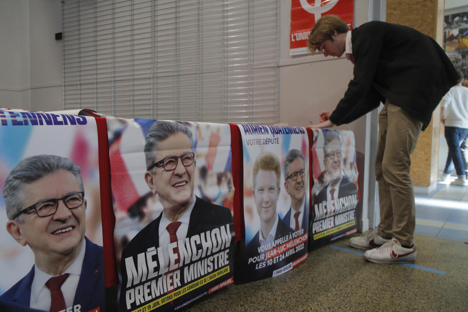 A supporter of far-left leader Jean-Luc Melenchon arranges electoral posters reading "Melenchon Prime Minister" before a local meeting, Thursday, May 5, 2022 in Lille, northern France. Jean-Luc Melenchon, who earned a third place finish in the presidential election, is trying to engineer a stunning comeback as the head of a coalition of leftist parties who have spent the past five years in the president's large shadow. Legislative elections will be held over two rounds of voting, on June 12 and 19.(AP Photo/Michel Spingler)