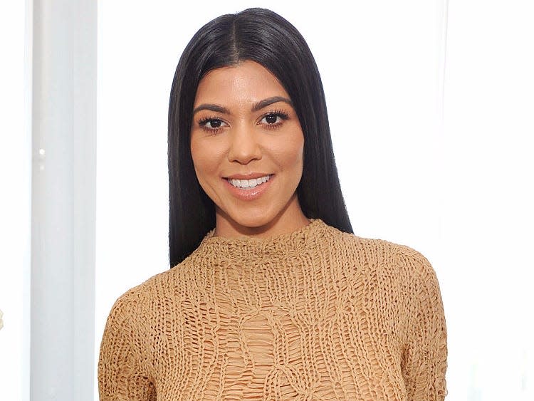 Kourtney Kardashian wears a tan knit sweater