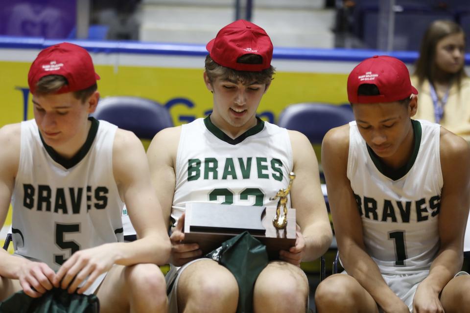 Avon's Connor Smith looks at his team's Class B2 Section V championship trophy. The trophy was passed down the line. Beside Smith are Brody McDowell and Jordan Murray.