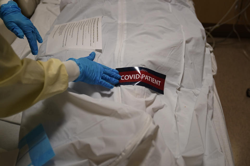 FILE - In this Jan. 9, 2021, file photo, a hospital worker places a "COVID Patient" sticker on a body bag holding a deceased patient at Providence Holy Cross Medical Center in the Mission Hills section of Los Angeles. Coronavirus hospitalizations are falling across the United States, but deaths have remained stubbornly high. (AP Photo/Jae C. Hong, File)
