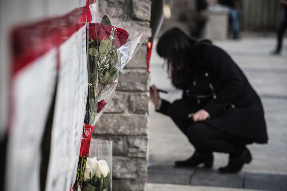 <p>Bouquets of flowers are placed at a makeshift memorial to the victims as a woman writes her condolences after a van mounted a sidewalk crashing into pedestrians in Toronto on Monday, April 23, 2018. (Photo: Aaron Vincent Elkaim/The Canadian Press via AP) </p>