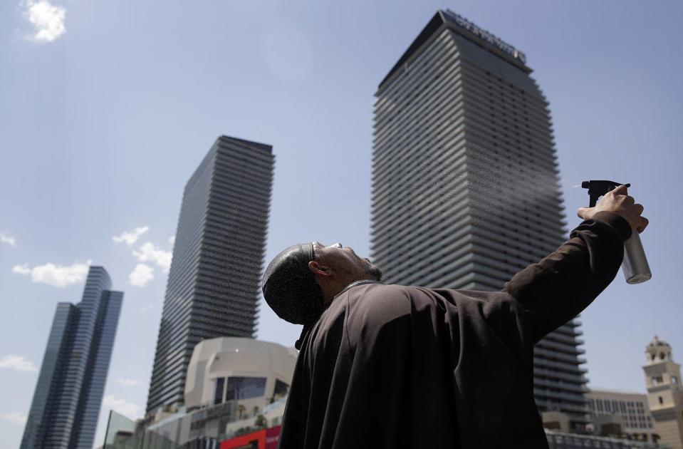 <p>Chris Mitchell sprays water on his face to cool off in a Darth Vader costume along the Las Vegas Strip, June 20, 2017, in Las Vegas. (John Locher/AP) </p>