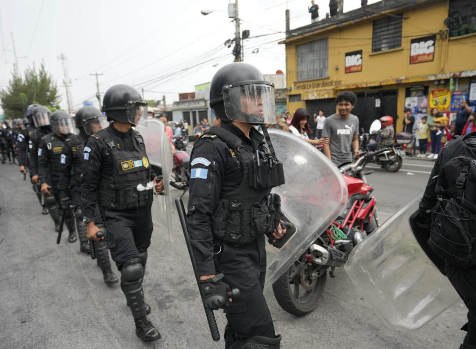Police in riot gear march on a highway blocked by demonstrators during a national strike, in Guatemala City, Tuesday, Oct. 10, 2023. People are protesting to support President-elect Bernardo Arévalo after Guatemala's highest court upheld a move by prosecutors to suspend his political party over alleged voter registration fraud. (AP Photo/Moises Castillo)
