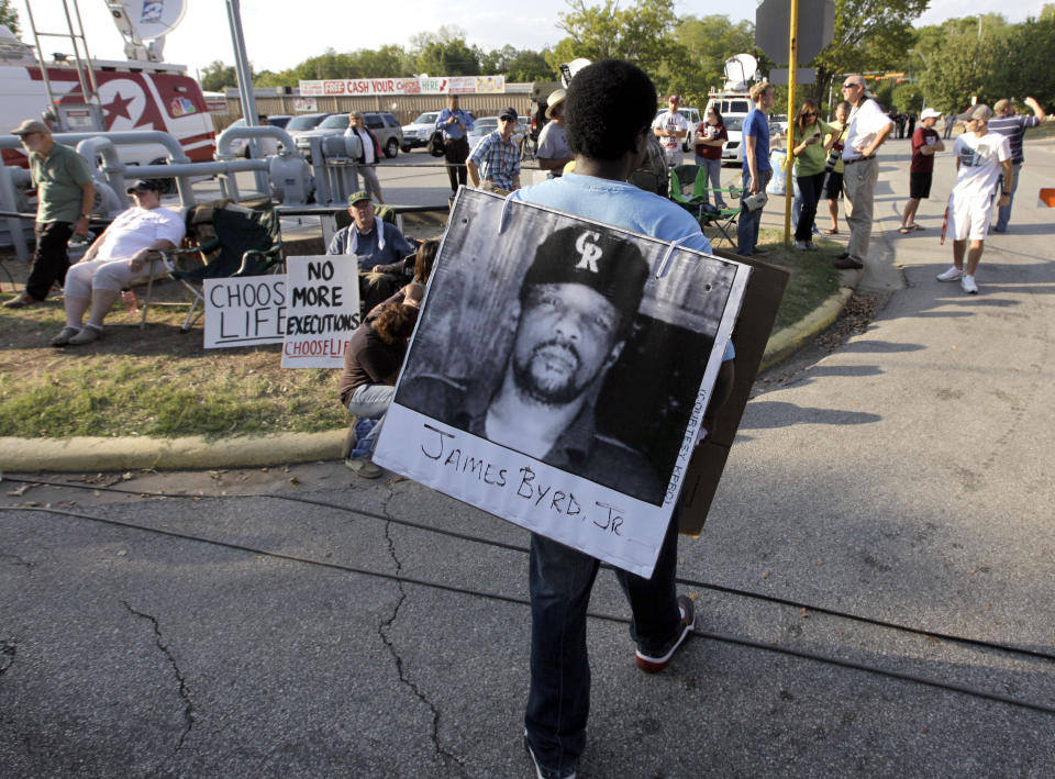 FILE - In this Sept. 21, 2011, file photo, Ricky Jason wears a photograph of James Byrd Jr. outside the Texas Department of Criminal Justice Huntsville Unit before the execution of Lawrence Russell Brewer in Huntsville, Texas. An East Texas town's history as the place where a black man, Byrd, was dragged to death by three white men nearly 21 years ago will again come to the forefront this week as the ringleader responsible for the brutal killing, John William King, is scheduled to be executed. (AP Photo/David J. Phillip, File)