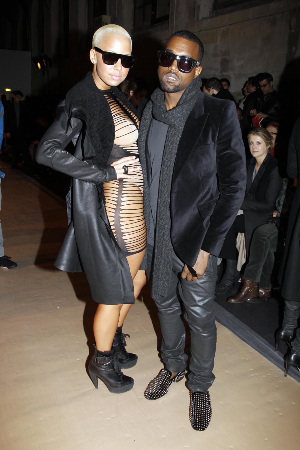 Kanye accessorizes his all-black ensemble with studded shoes and a lady dressed like a prostitute. We couldn't even show you the frontal view, but lets say nothing was left to the imagination.