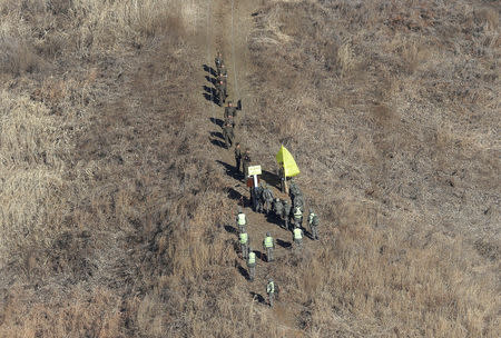 North Korean army soldiers, top, head to cross the Military Demarcation Line inside the Demilitarized Zone (DMZ) to inspect the dismantled South Korean guard post as South Korean army soldiers watch in the central section of the inter-Korean border in Cheorwon, December 12, 2018. Ahn Young-joon/Pool via REUTERS