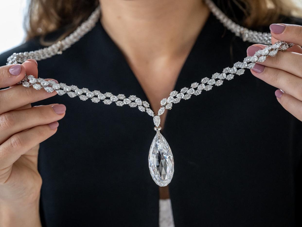 This photograph taken on May 8, 2023, shows an employee of Christie's auction house holding the "Briolette of India" a 90.36 carats colourless (D) diamond, a diamond necklace expected to fetch at least 10 million USD at the World of Heidi Horten sale in Geneva. - Christie's launch the sale of hundreds of jewels that belonged to Austrian billionaire Heidi Horten, whose German businessman husband made his fortune under the Nazis.