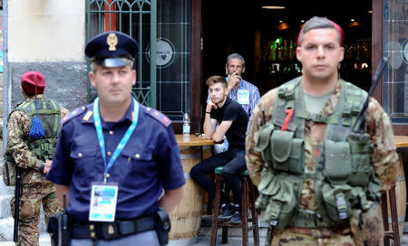 People sit in a pub as Italian Army soldiers patrol in Taormina where leaders from the world's major Western powers will hold their annual summit, Italy, May 24, 2017. REUTERS/Guglielmo Mangiapane