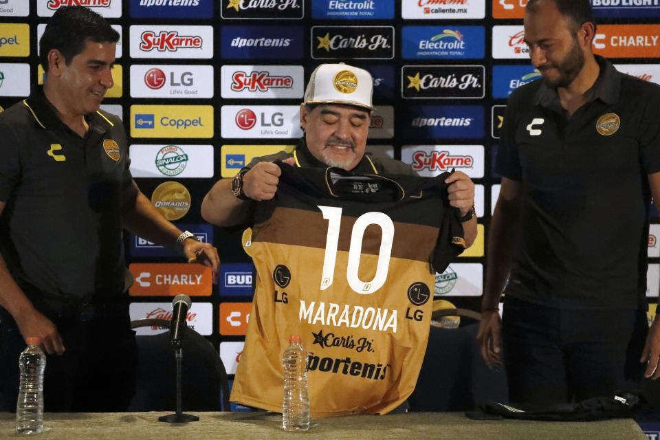Former soccer great Diego Maradona shows his team jersey during a press conference where he was presented as the new manager of the Dorados of Sinaloa, in Culiacan, Mexico, Monday, Sept. 10, 2018. Maradona, whose public battles with cocaine made him soccer's poster child for the perils of substance abuse, is setting up camp in Mexico's drug cartel heartland as the new coach of a second-tier team. (AP Photo/Marco Ugarte)