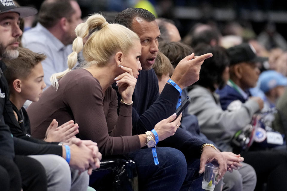 Minnesota Timberwolves minority owner Alex Rodriguez, center right, talks with girlfriend Jac Cordeiro, center left, as they watch play in the first half of an NBA basketball game against the Dallas Mavericks, Monday, Feb. 13, 2023, in Dallas. (AP Photo/Tony Gutierrez)