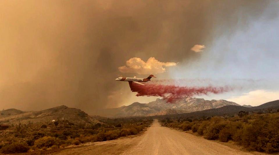 This photo provided by the National Park Service Mojave National Preserve shows a tanker making a fire retardant drop over the York fire in Mojave National Preserve on Saturday, July 29, 2023. A massive wildfire burning out of control in California's Mojave National Preserve is spreading rapidly amid erratic winds. Meanwhile, firefighters reported some progress Sunday against another major blaze to the southwest that prompted evacuations.