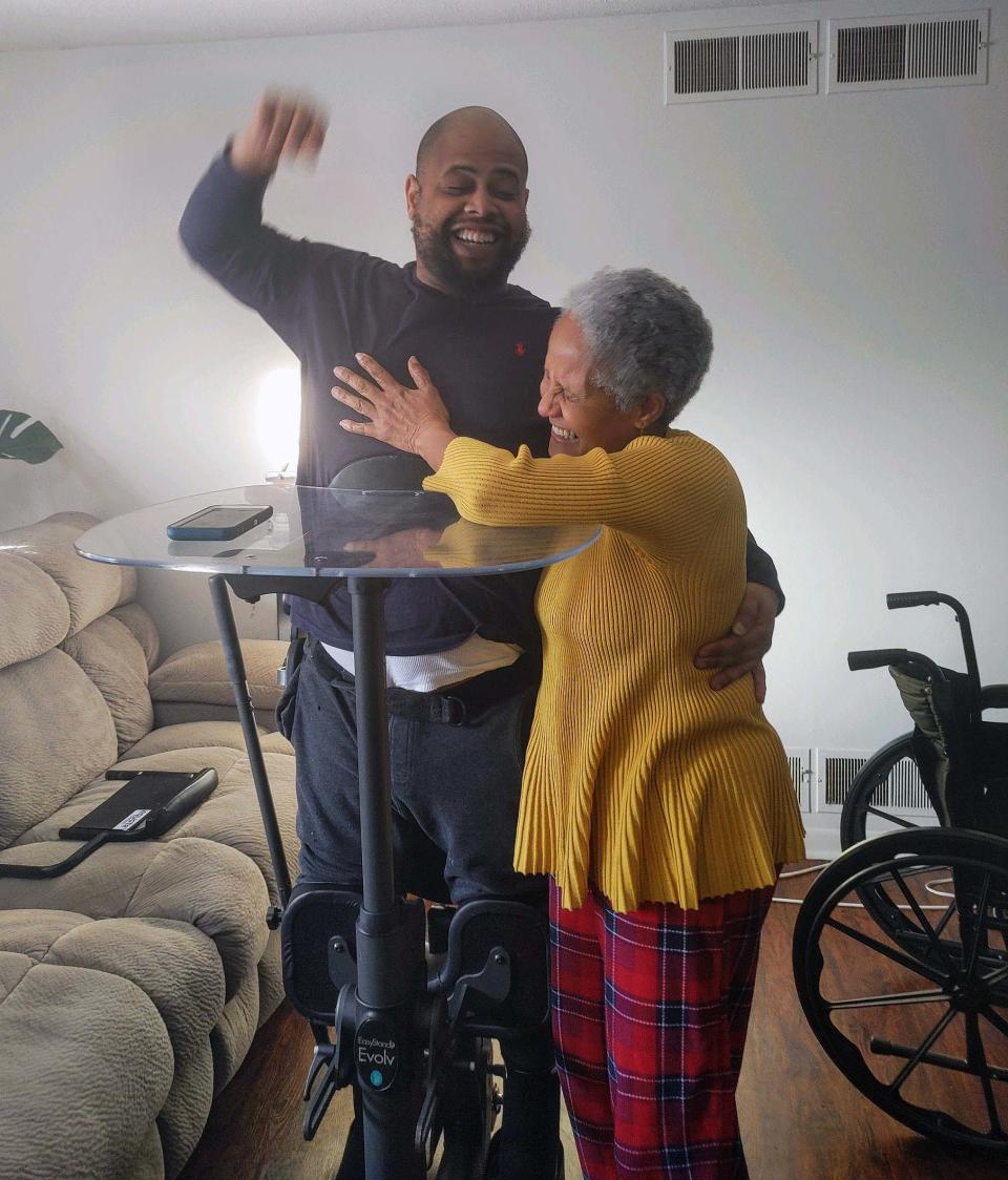 Michael Patterson, 38, (left) stands up for the first time in over 15 years in December with the help of a standing frame.