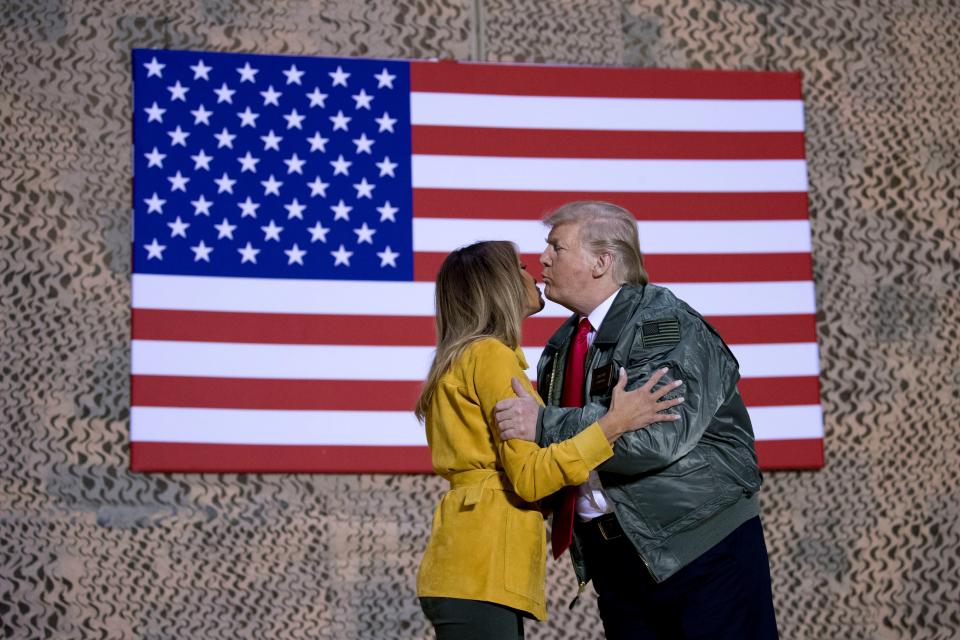 President Donald Trump kisses first lady Melania Trump during a hanger rally at Al Asad Air Base, Iraq, on Dec. 26, 2018. President Donald Trump, who is visiting Iraq, says he has 'no plans at all' to remove US troops from the country.