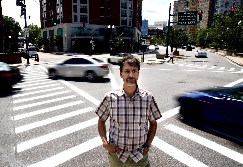 Jamie Pahigian, a member of the Providence Streets Coalition, stands at the intersection of Memorial Boulevard and Exchange Terrace in Providence, a particularly dangerous spot for pedestrians.