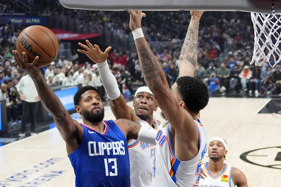 Los Angeles Clippers forward Paul George, left, shoots as Oklahoma City Thunder guard Shai Gilgeous-Alexander, center and forward Kenrich Williams defend during the first half of an NBA basketball game Tuesday, Jan. 16, 2024, in Los Angeles. (AP Photo/Mark J. Terrill)