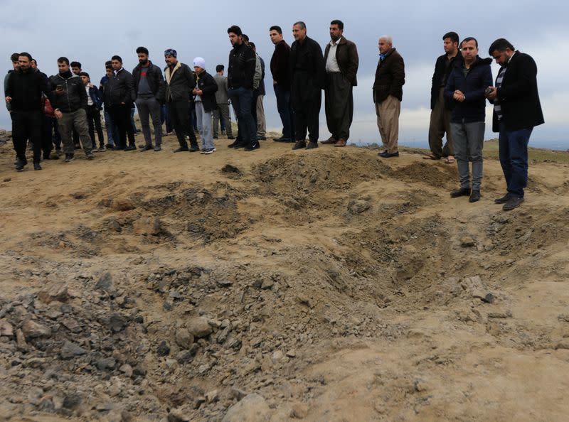 Residents look at a crater caused by a missile launched by Iran on U.S.-led coalition forces on the outskirts of Duhok