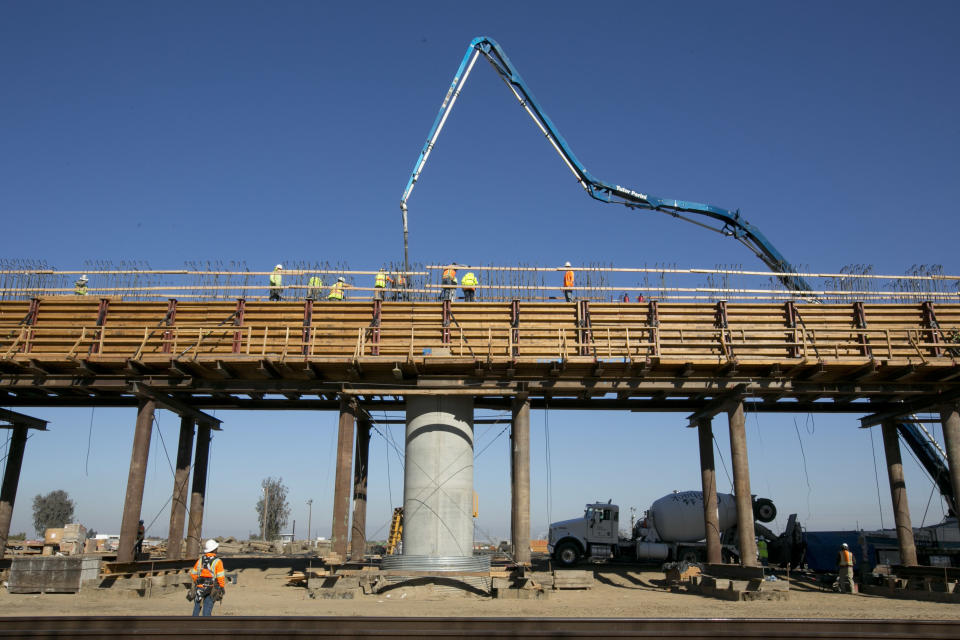 In this photo taken, Wednesday, Dec. 6, 2017, workers pour concrete on to one of the elevated sections of the high-speed rail that will cross over the San Joaquin River, near Fresno, Calif. Officials are raising the projected cost of the first phase of California's bullet train by 35 percent, to $10.6 billion. The extra $2.8 billion comes because of delays in obtaining rights of way and barriers along parts of the track of the 199-mile segment in the Central Valley that is partly under construction. The California High Speed Rail Authority board discussed the increase Tuesday, Jan. 16, 2018. (AP Photo/Rich Pedroncelli)