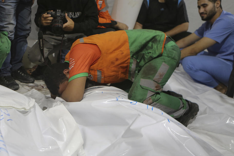 Personal palestino de defensa civil llora sobre el cuerpo de un colega, que llegó muerto al hospital de Shifa, después de que ataques aéreos israelíes atacaran un puesto de defensa civil en Ciudad de Gaza, en el centro de la Franja de Gaza, el lunes 16 de octubre de 2023. (AP Foto/Abed Khaled)
