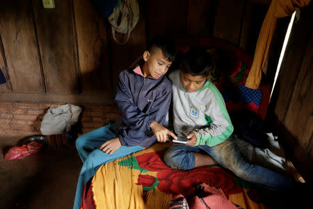 Children of the Mbya Guarani ethnic group look at a smartphone, in Isla Jovai Teju, Paraguay May 9, 2019. Picture taken May 9, 2019. REUTERS/Jorge Adorno