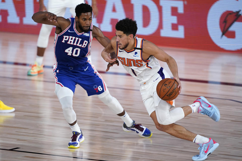 Phoenix Suns guard Devin Booker (1) drives past Philadelphia 76ers forward Glenn Robinson III (40) during the first half of an NBA basketball game Tuesday, Aug. 11, 2020, in Lake Buena Vista, Fla. (AP Photo/Ashley Landis, Pool)