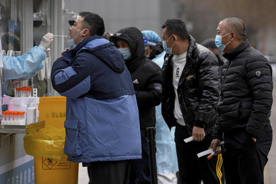 A man gets a throat swab for the COVID-19 test at a mobile coronavirus testing facility a residential area in Beijing, Wednesday, Jan. 19, 2022. With just over two weeks before the opening of the Beijing Winter Olympics, residents of the Chinese capital say they’re disappointed at not being able to attend events because of coronavirus restrictions that have seen parts of the city placed under lockdown. (AP Photo/Andy Wong)