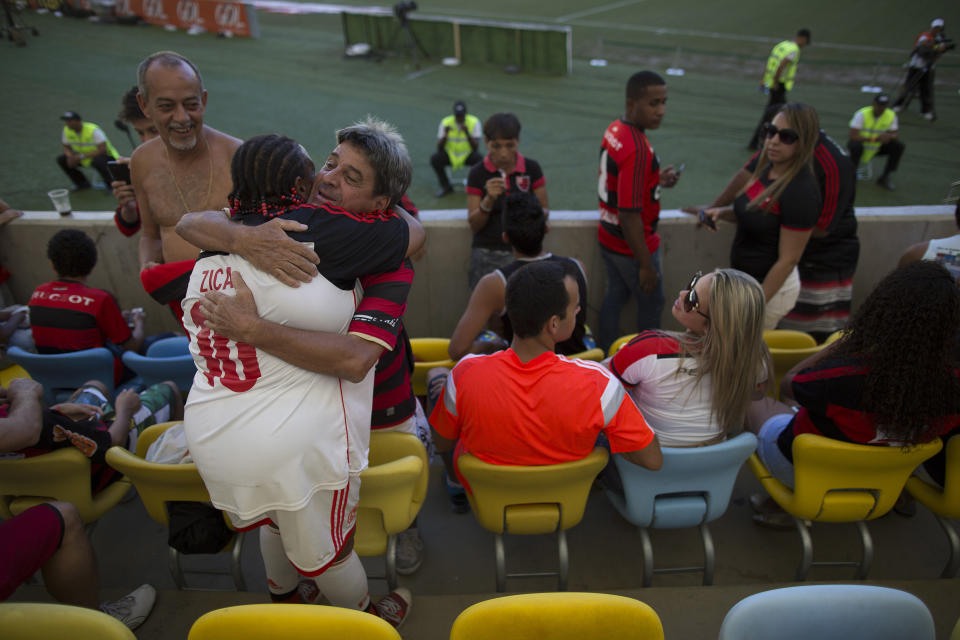 In this May 4, 2014 photo, Maria Boreth de Souza, alias Zica, front left, hugs a friend at Maracana stadium before a match between their team Flamengo with Palmeiras in Rio de Janeiro, Brazil. "I go to every game Flamengo plays in Maracana where I am always greeted with open arms by players and fans of Flamengo and the teams they play against. They all hug me and ask for my autograph," she said, adding that in 2010 Flamengo made her an honorary member. (AP Photo/Leo Correa)