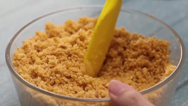 Mixing biscuit crumbs with a yellow spatula