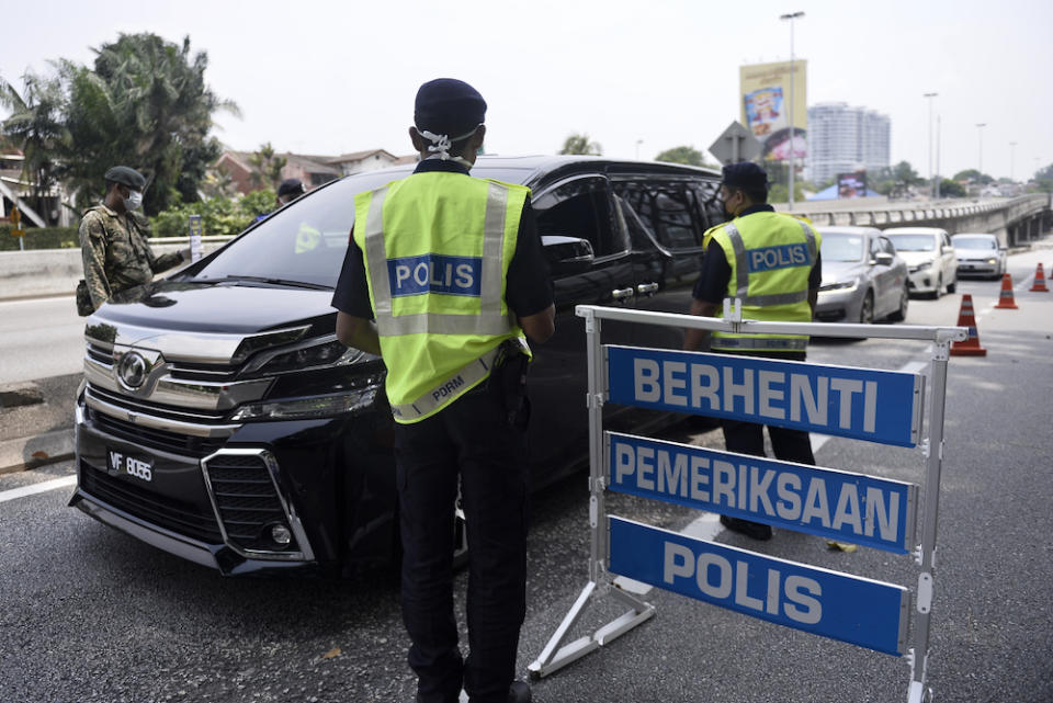 Soldiers and police officers conducting checks at a roadblock on day five of the movement control order (MCO) in Sri Hartamas March 22,2020. — Picture by Miera Zulyana